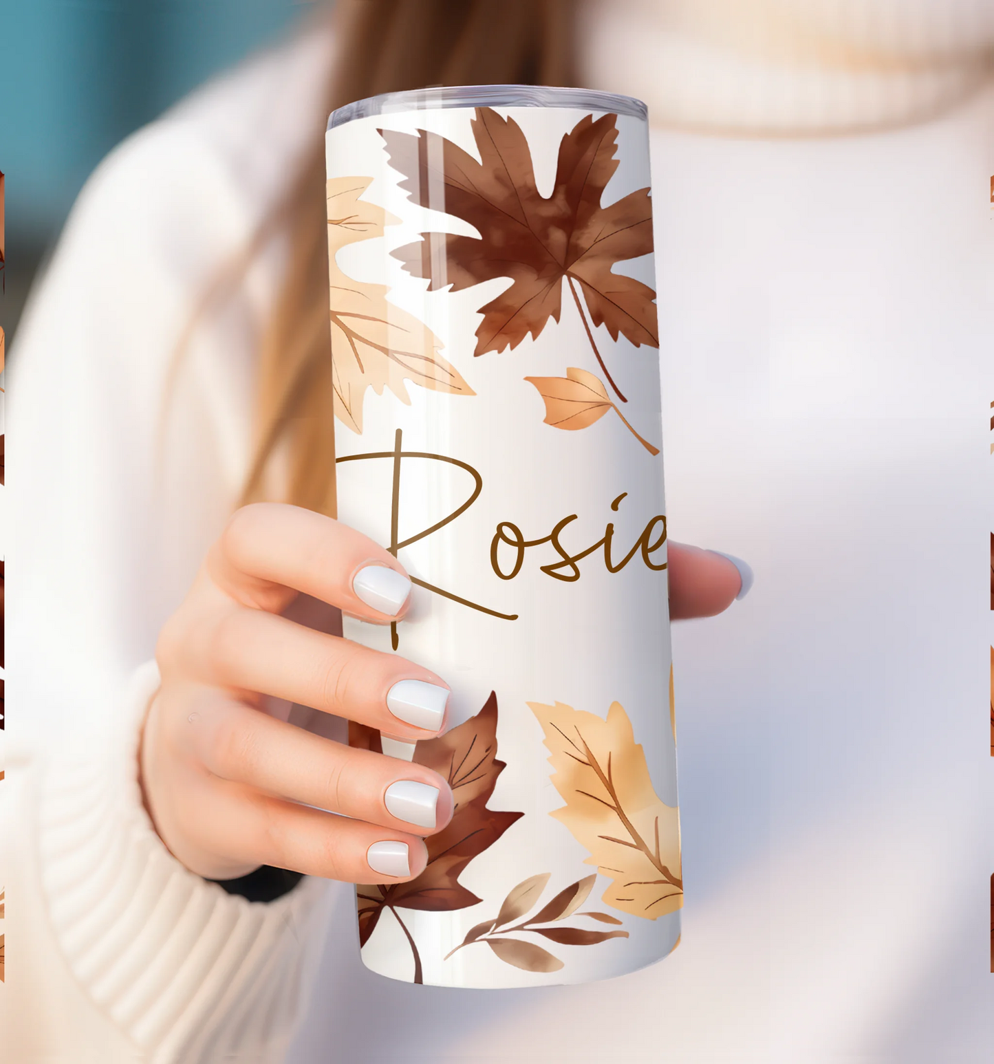 Tumbler with autumn leaf design and 'Rosie' text held by a person.