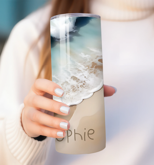 Person holding a tumbler with a beach design and 'Sophie' branding.
