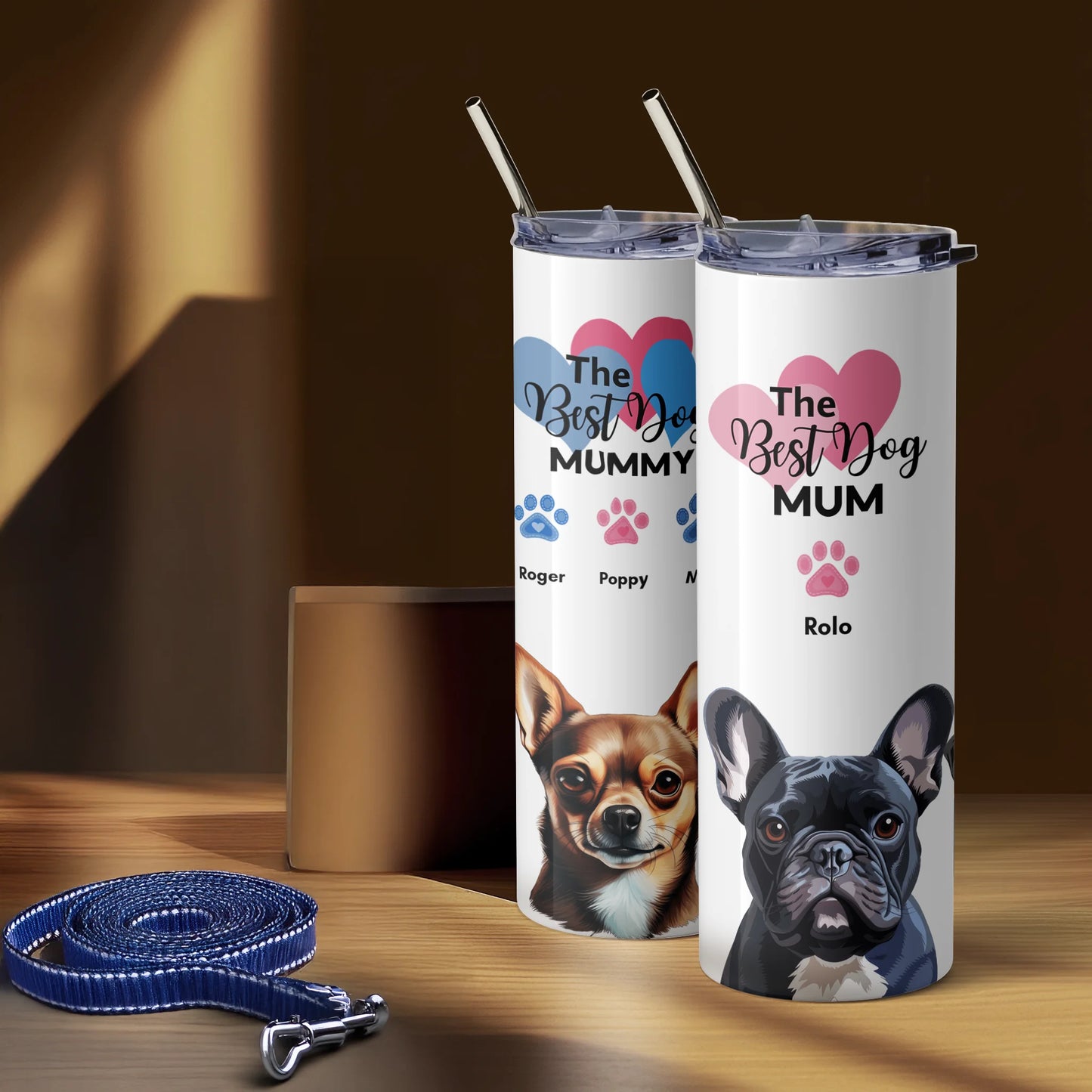 Two tumblers with dog illustrations and text on a wooden surface with a leash.
