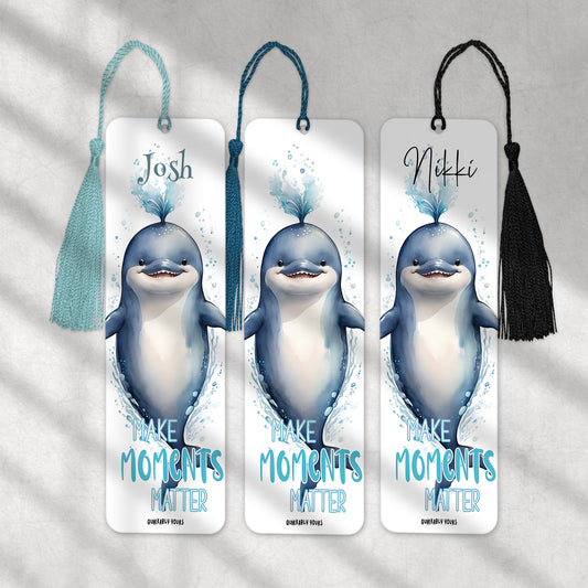Three bookmarks with cartoon dolphins and personalized names on a light gray background