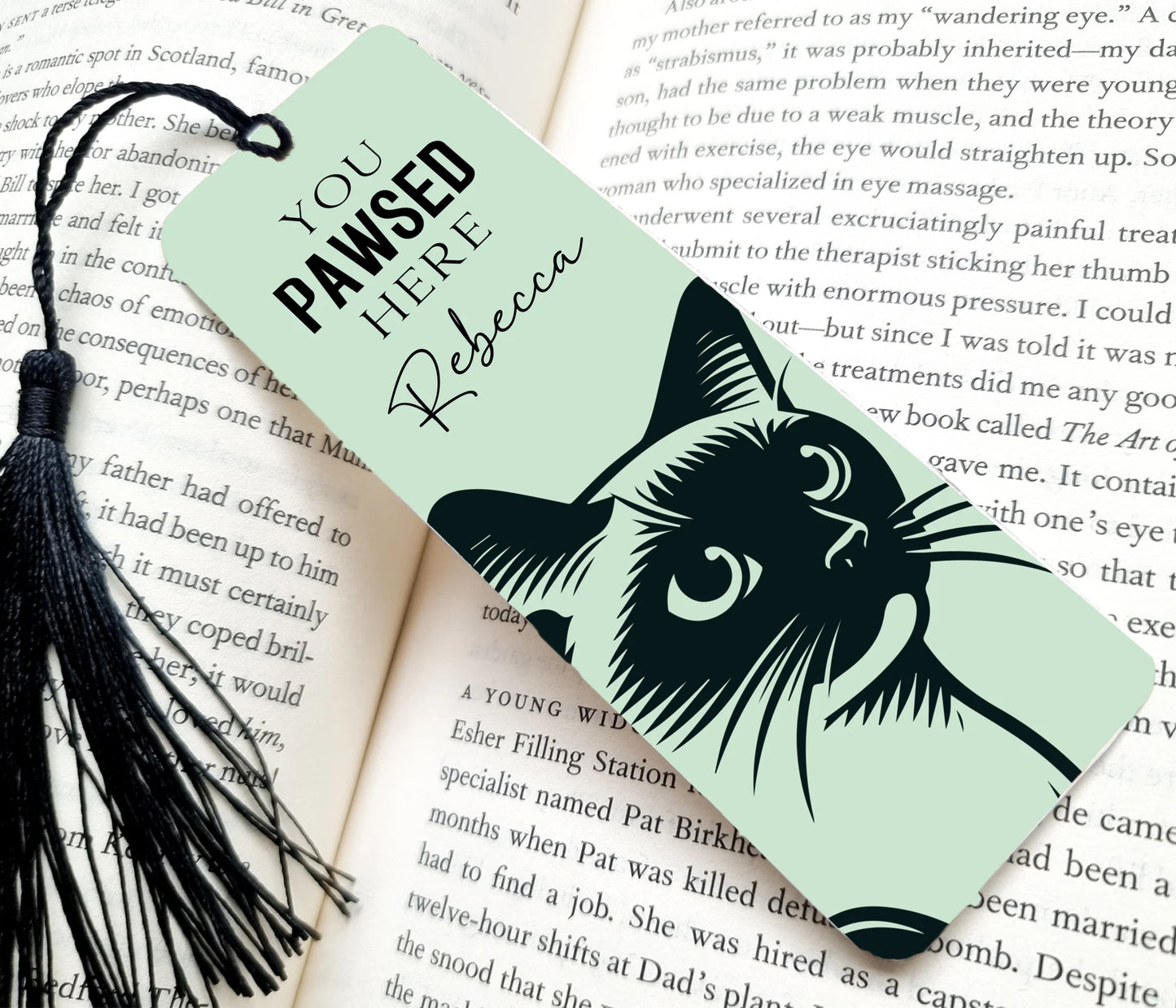 Bookmark with cat illustration and text 'You pawsed here' on an open book