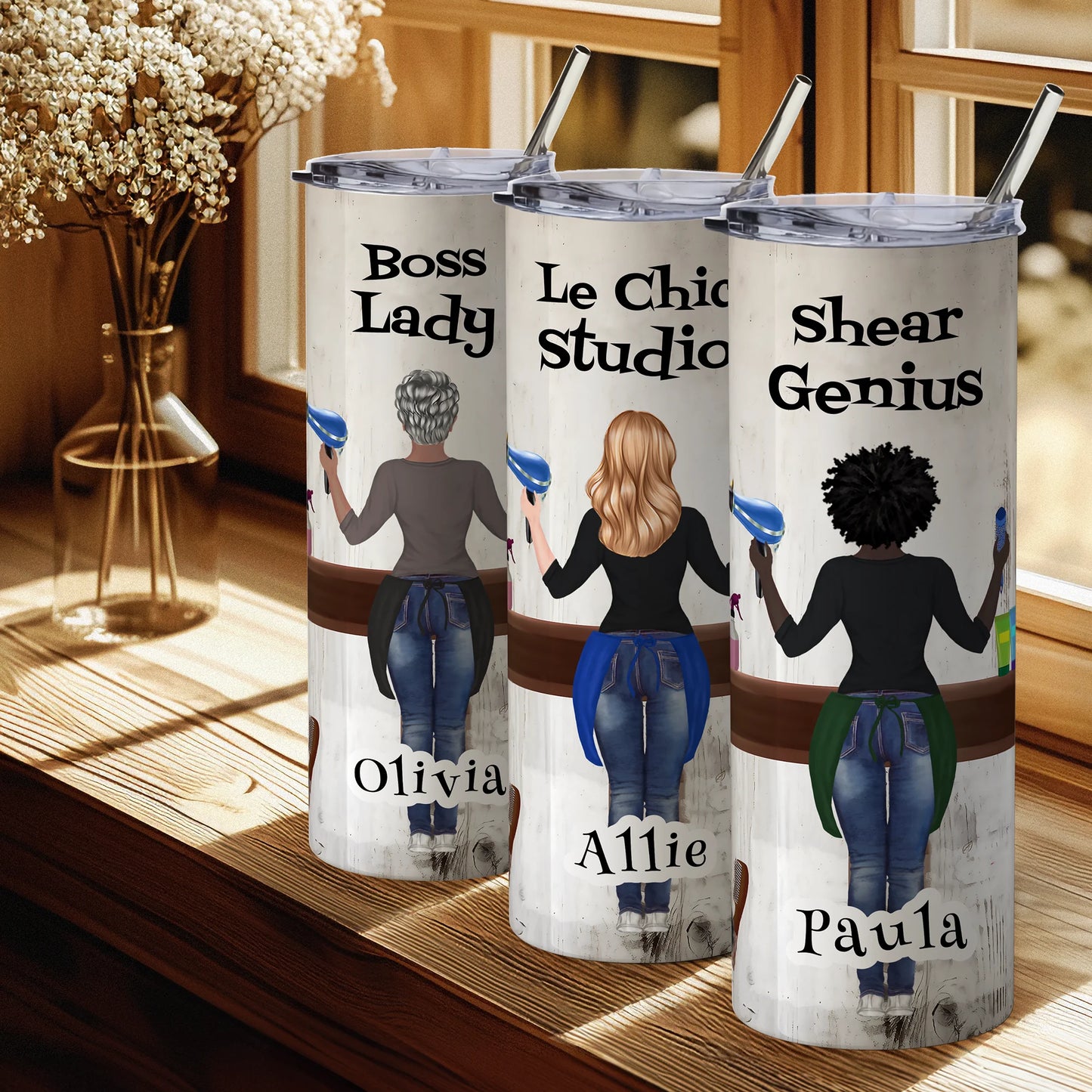 Three insulated tumblers with personalized designs and names on a wooden surface.