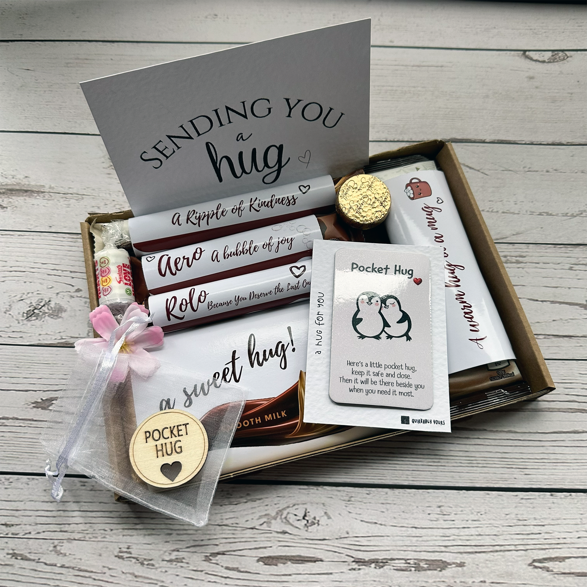Chocolate Hug Box with token and sweets. Box of chocolates with a card and small gift items on a wooden surface