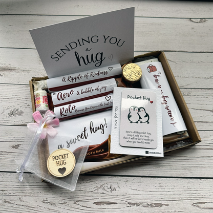 Chocolate Hug Box with token and sweets. Box of chocolates with a card and small gift items on a wooden surface