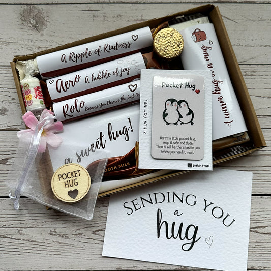 Hug in a box Gift set with chocolates, a card, and a small pouch labeled 'Pocket Hug' on a wooden surface.