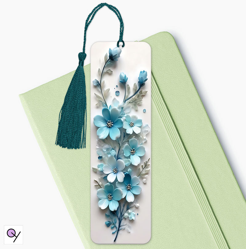 Aluminum bookmark featuring a striking 3D effect floral print of blue and white flowers, elegant and vibrant. The bookmark is sitting on a green diary.