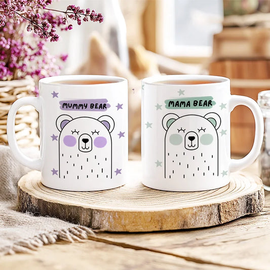 Two mugs labeled 'Mummy Bear' and 'Mama Bear' on a wooden coaster with a blurred background.