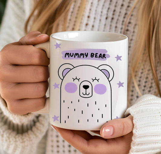 Person holding a white mug with a bear design and 'Mummy Bear' text.