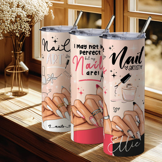 Three tumbler cups with nail art designs and text on a wooden surface.