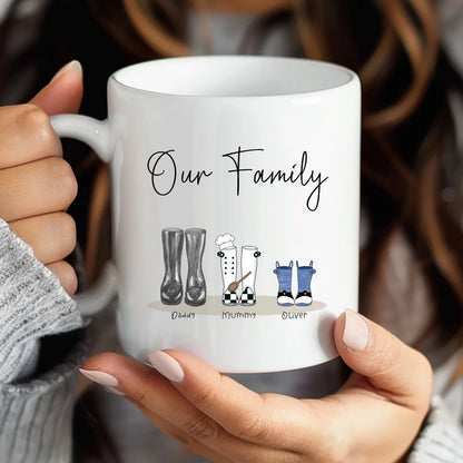 White mug with 'Our Family' design held by a person, featuring illustrations of family members.