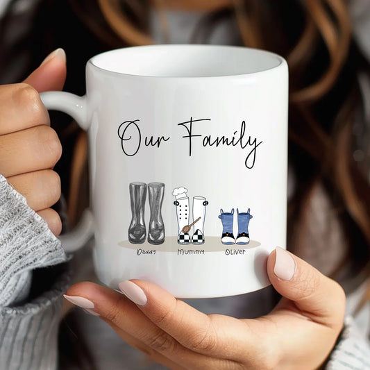 White mug with 'Our Family' design held by a person, featuring illustrations of family members.