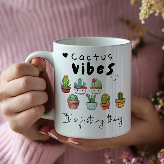 Mug with 'Cactus Vibes, It's just my thing' text and cactus illustrations held by a person.