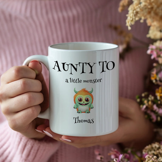 Person holding a mug with 'Aunty to a little monster' text and a cartoon monster design.