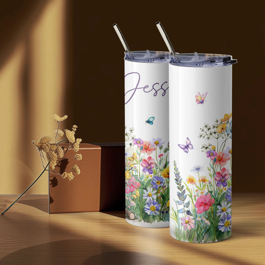 Two tumblers with floral designs and straws on a wooden surface.