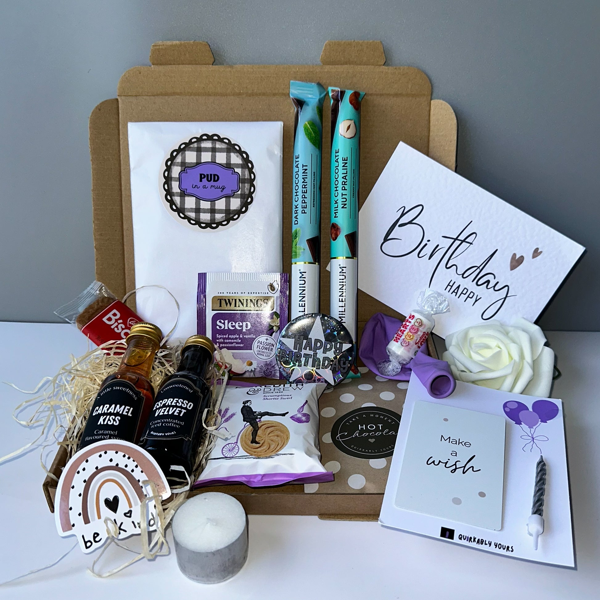 Make a wish birthday celebration gift set Gourmet gift basket with snacks, drinks, and a birthday card on a white surface.
