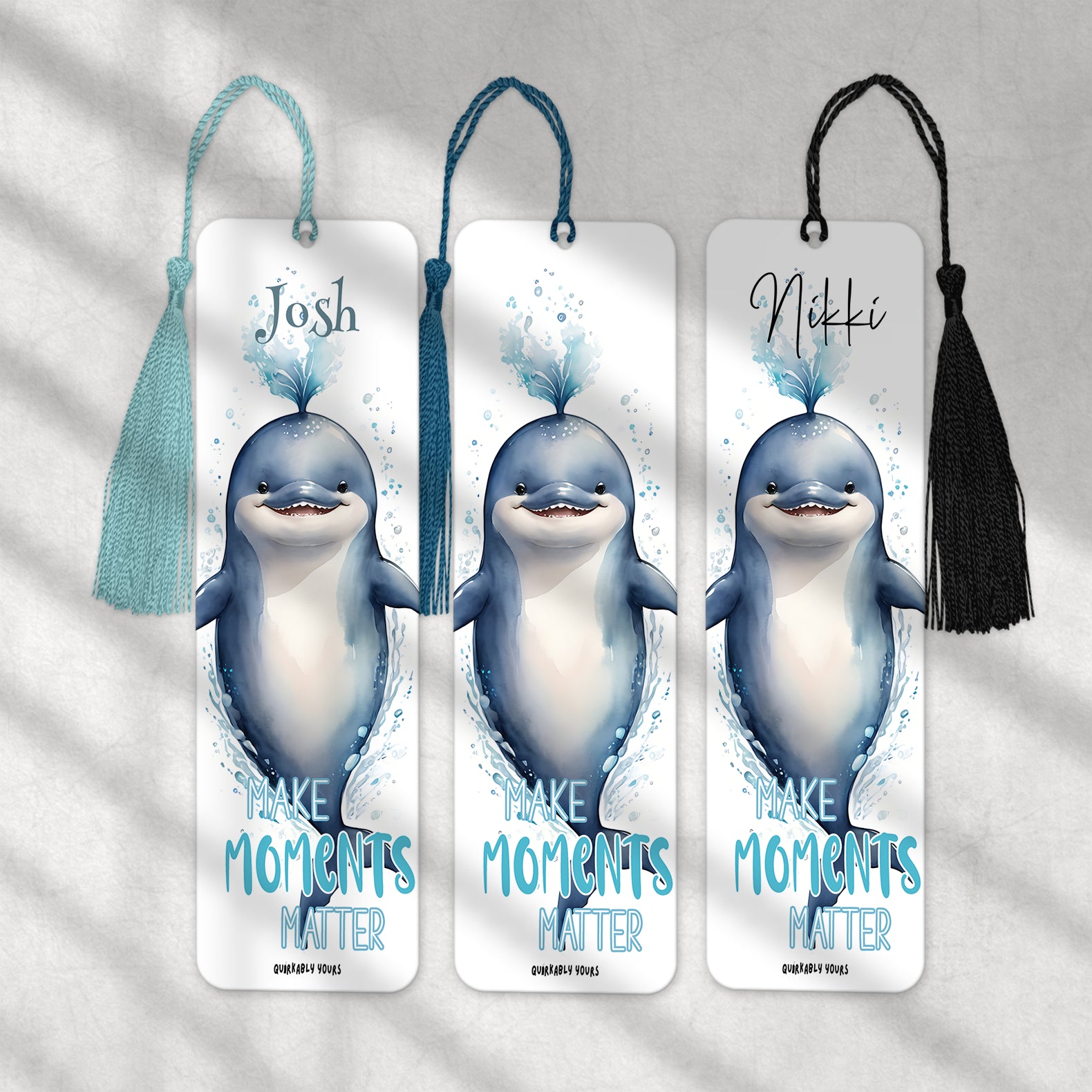 Three bookmarks with cartoon dolphins and personalized names on a light gray background